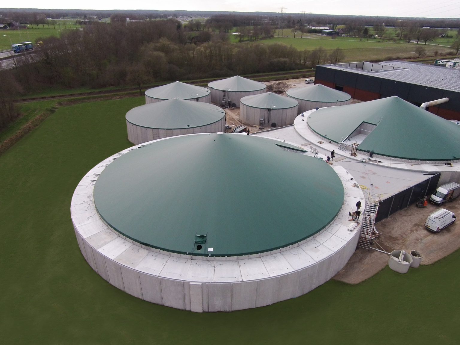 Seven green tensioned covers on concrete silos