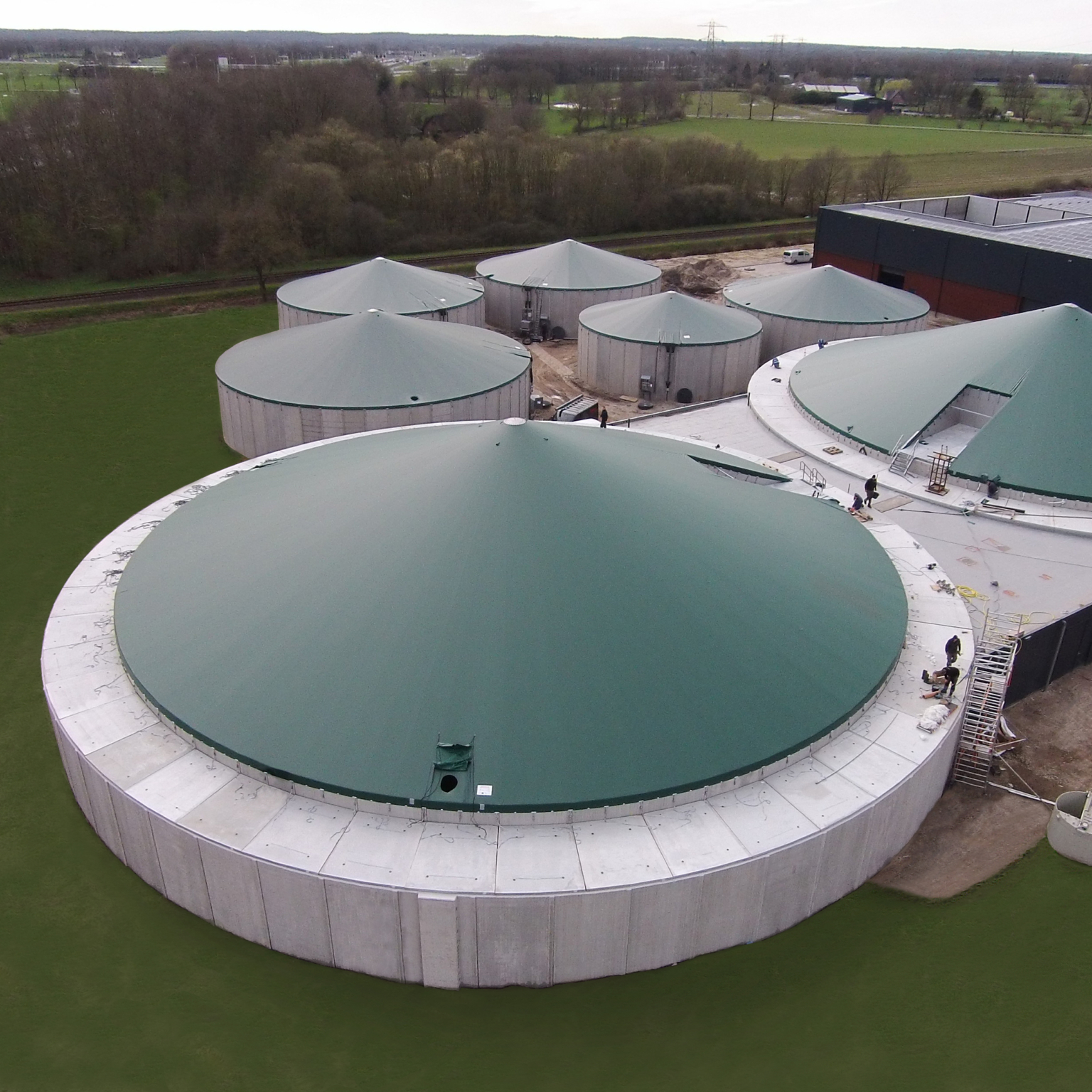 Seven green tensioned covers on concrete silos