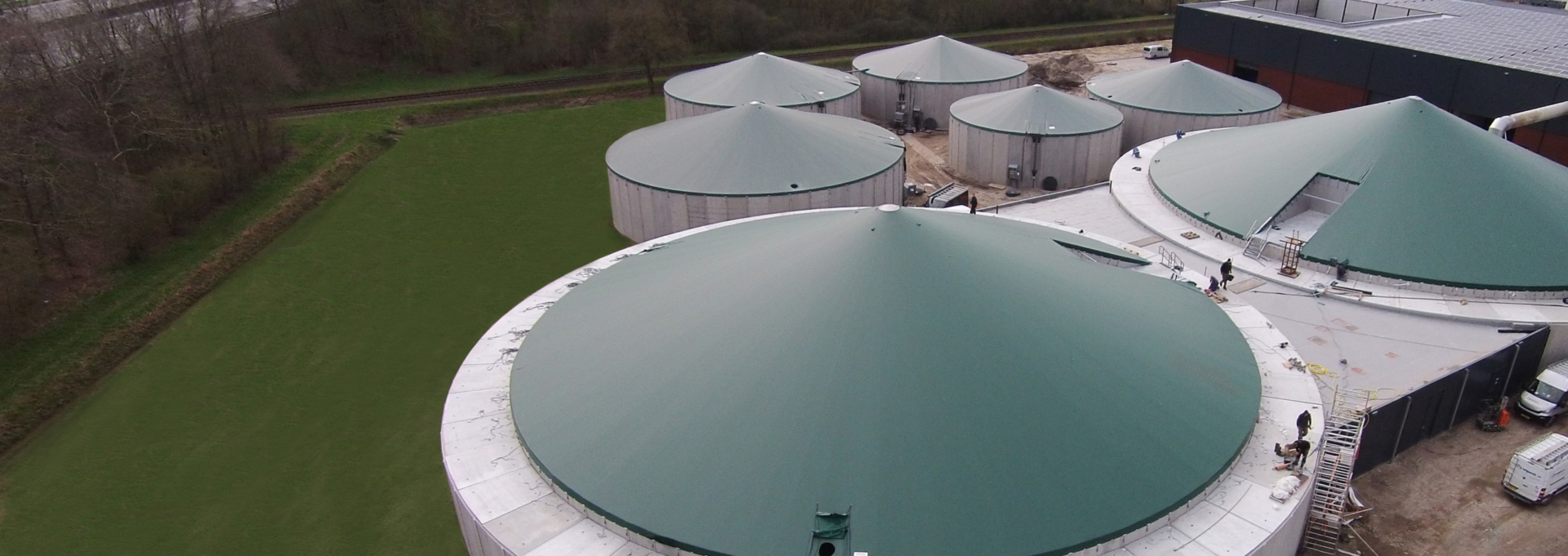 Seven green tensioned covers on concrete silos