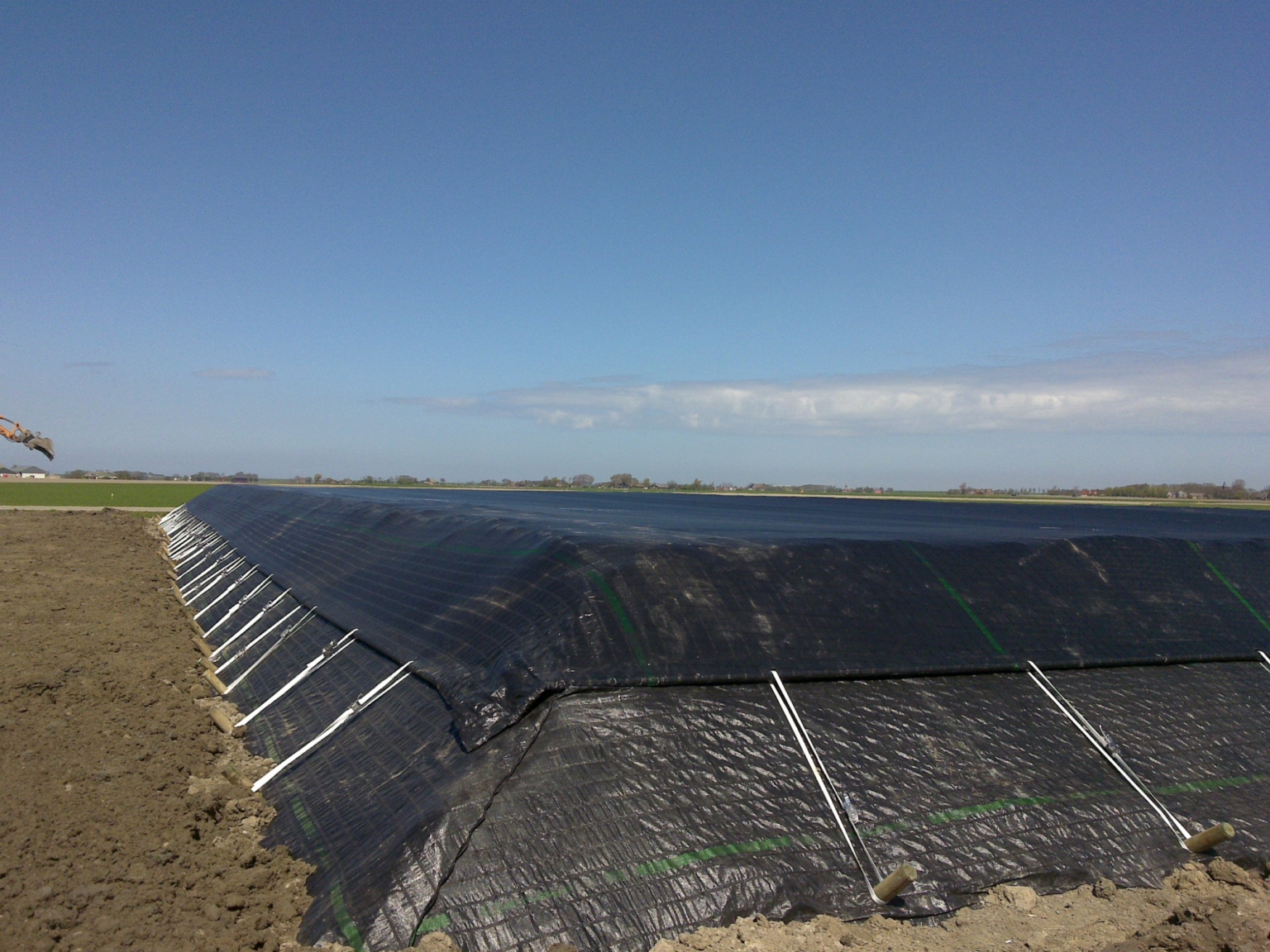 Tensioned cover mounted on a water reservoir anchored at the toe of the dike