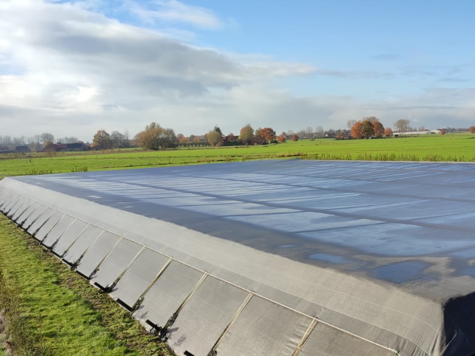 Tensioned cover mounted on a water basin anchored at the toe of the dike