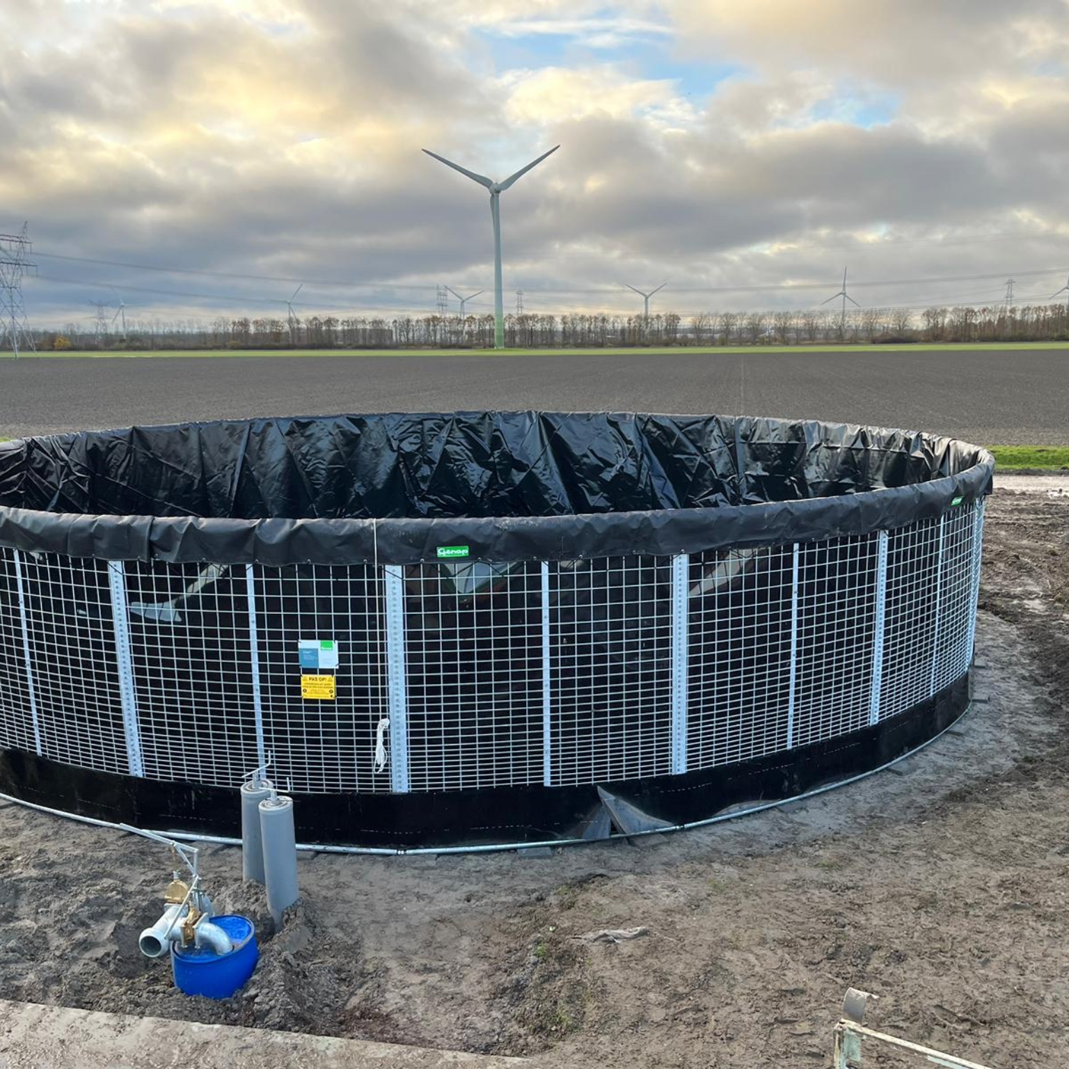 Slurry silo with wind turbines in the background